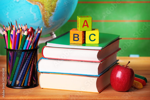 Stack of books, red apple, globe and pencils photo