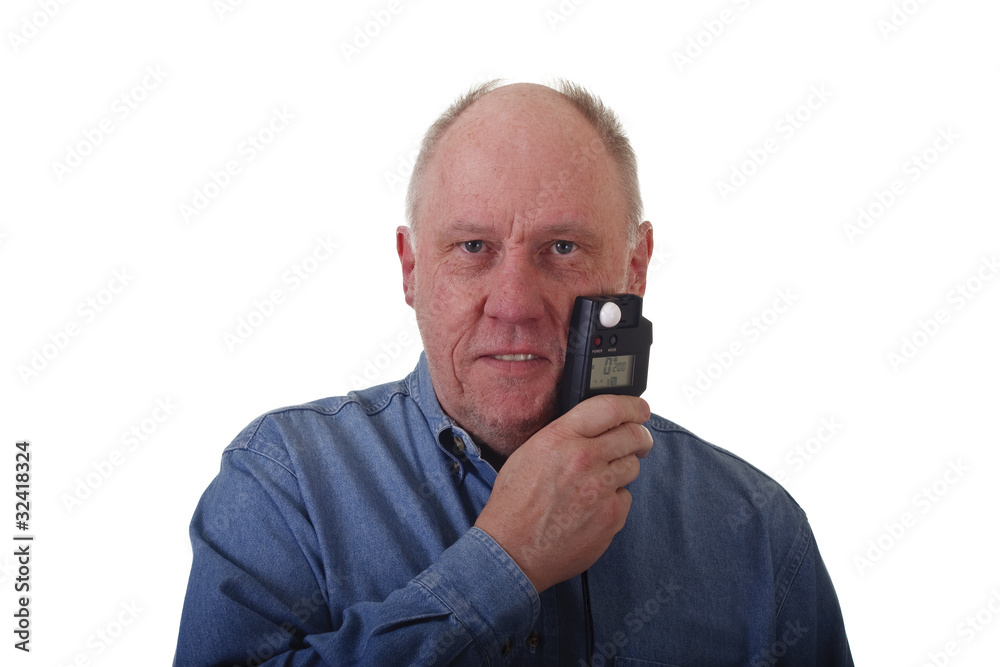 Older Man in Blue Denim Shirt Holding Light Meter to Face Older Man in Blue Denim Shirt Holding Light Meter to Face