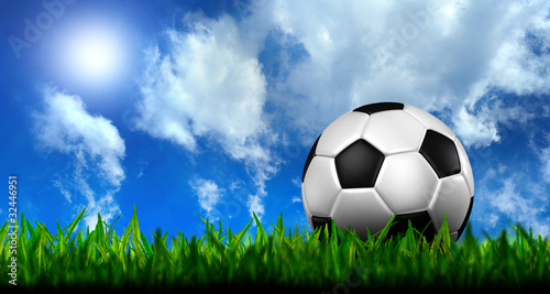 football in green grass over a blue sky