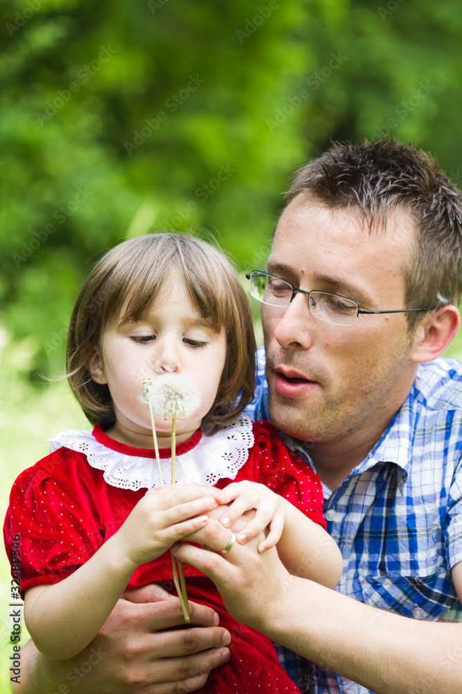Obraz premium Happy father playing with his daughter in beautiful green grass