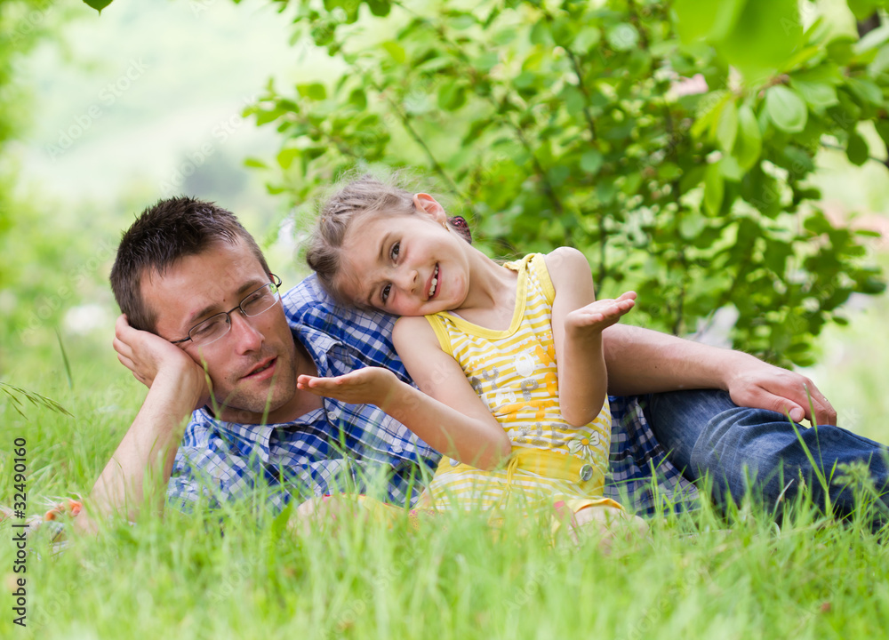 Fototapeta premium Happy father playing with his daughter in beautiful green grass