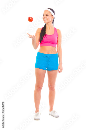 Smiling young healthy girl in sportswear throwing apple up © Alliance