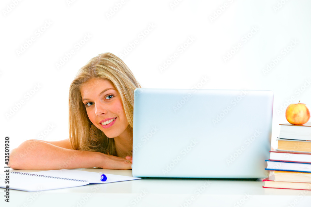 Sitting at table smiling teen girl looking out from laptop. Sitting at table smiling teen girl looking out from laptop.