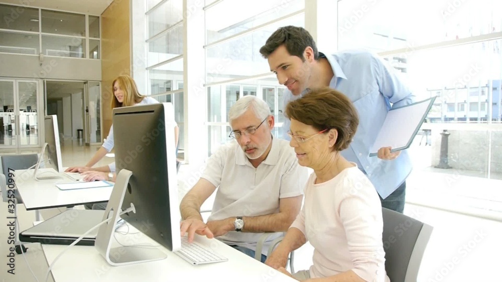 Group of senior people with trainer in front of computer Group of senior people with trainer in front of computer