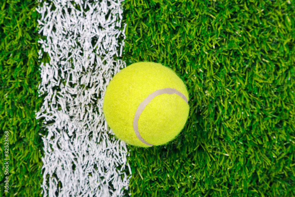 Tennis ball on grass from above.