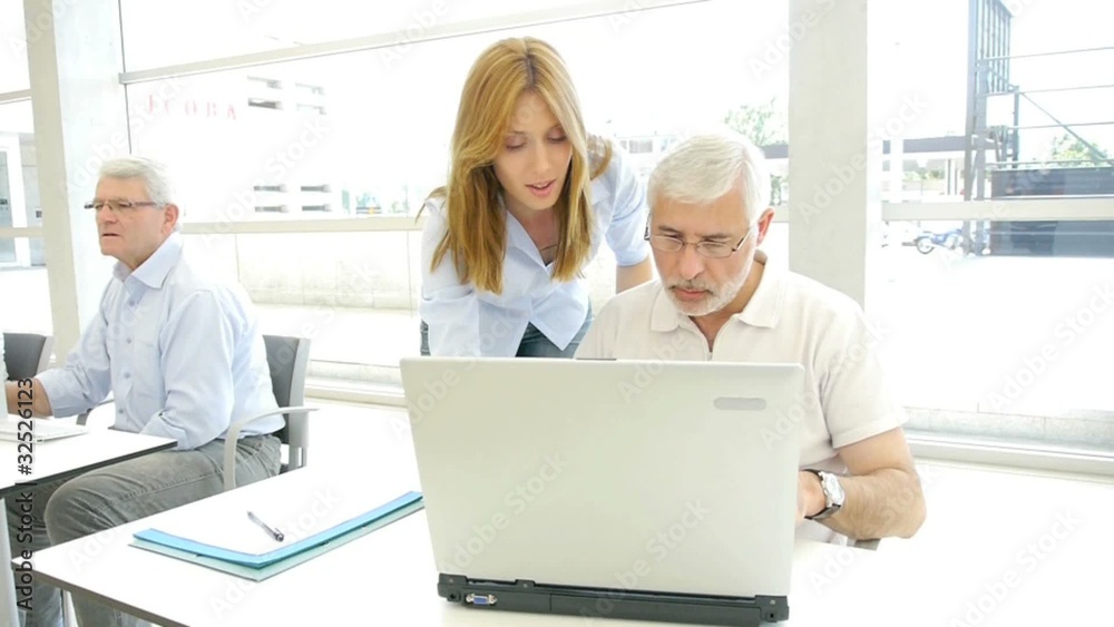 Group of senior people with trainer in front of computer Group of senior people with trainer in front of computer