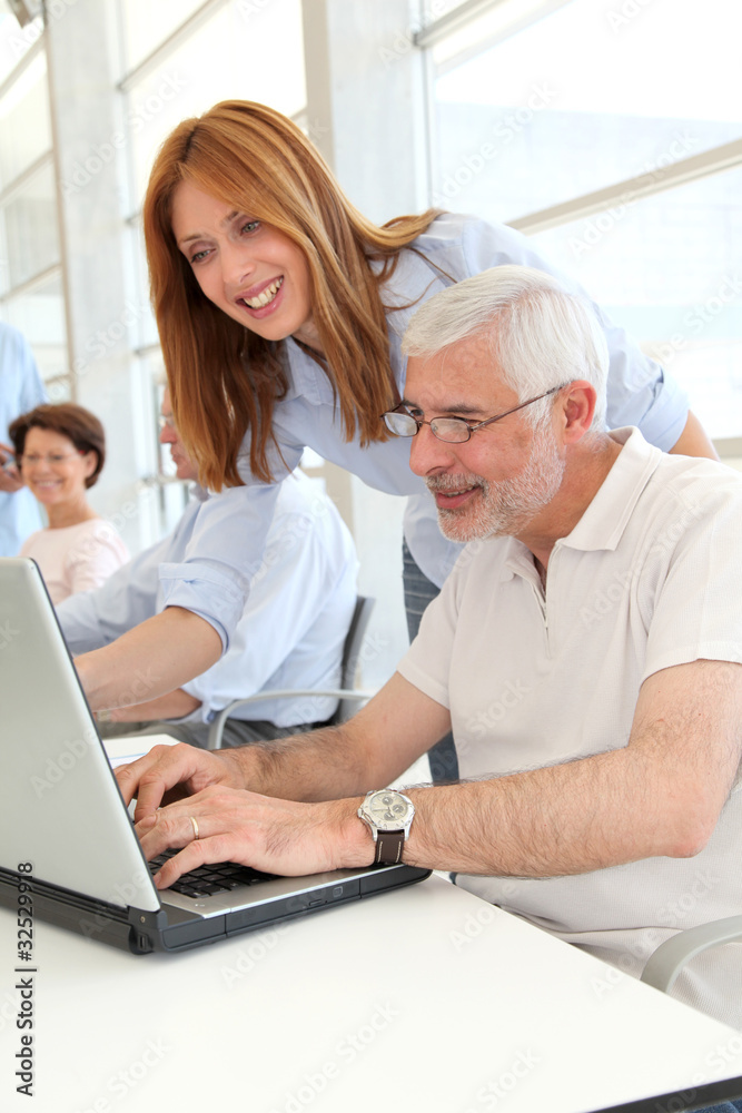 Senior man with trainer in front of laptop computer Senior man with trainer in front of laptop computer