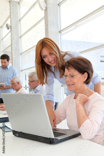 Senior woman with trainer in front of laptop computer
