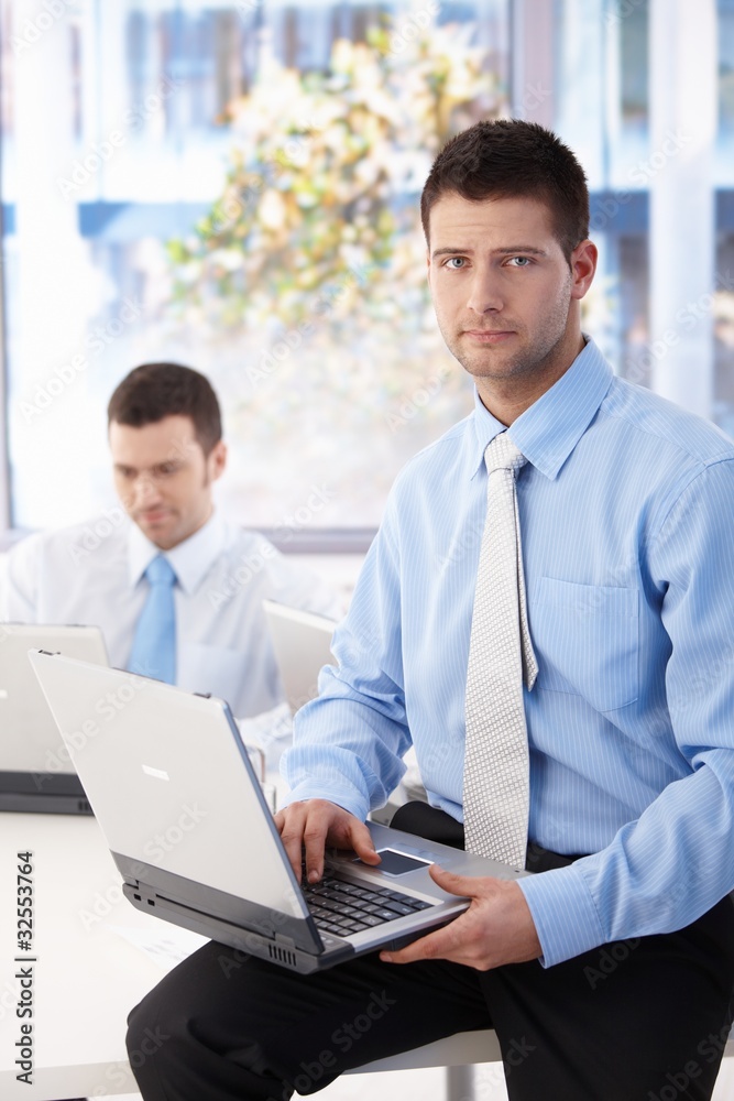 Handsome businessman sitting on top of desk Handsome businessman sitting on top of desk