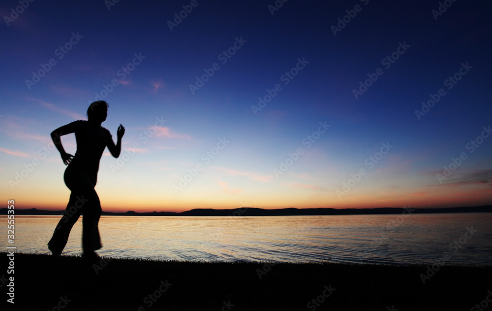 Young woman running on a beach at sunset