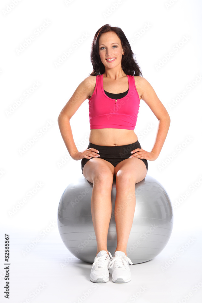 Happy young woman in gym using exercise ball
