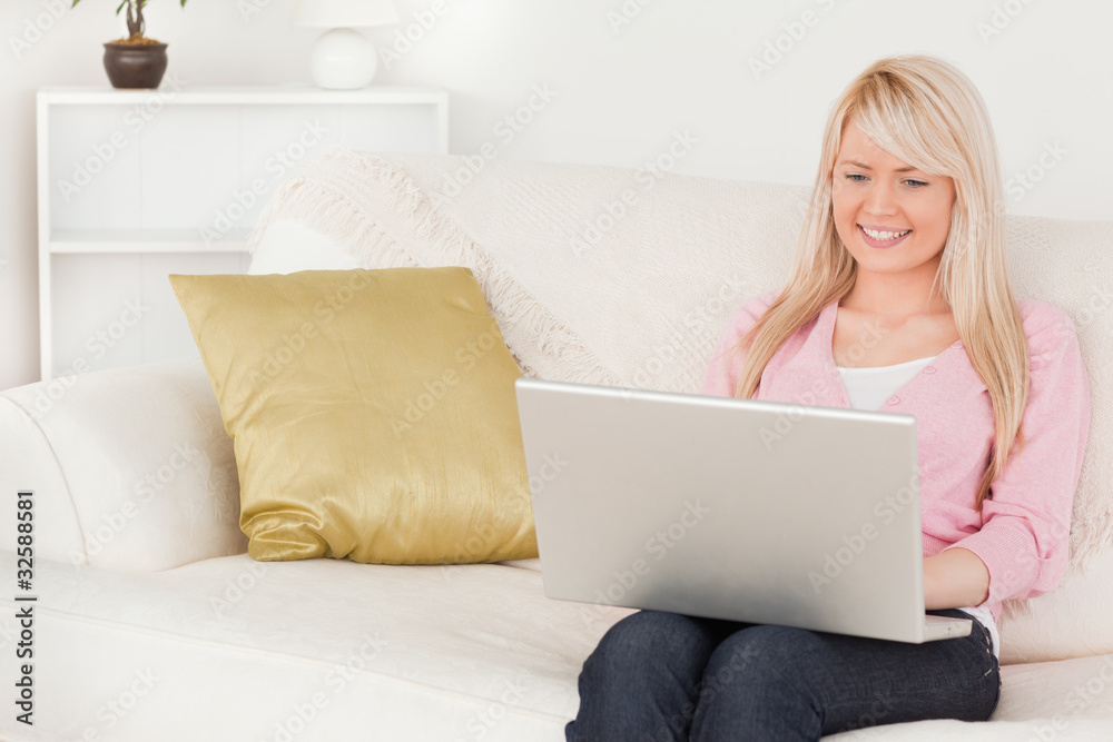 Young attractive woman relaxing with a laptop while sitting on a Young attractive woman relaxing with a laptop while sitting on a