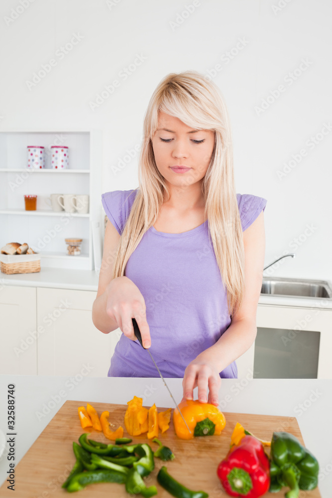 Beautiful blonde female cutting peppers in modern kitchen interi Beautiful blonde female cutting peppers in modern kitchen interi