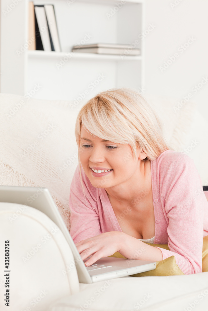 Young good looking female relaxing with a laptop while lying on Young good looking female relaxing with a laptop while lying on