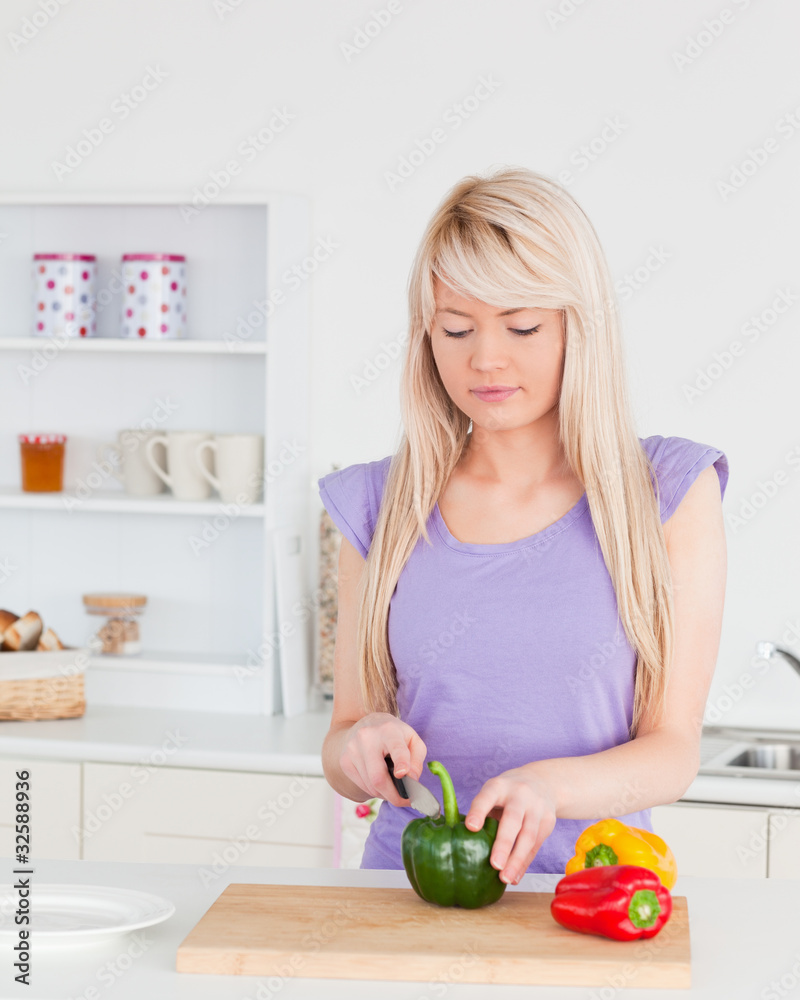 Attractive blonde woman cutting vegetables in modern kitchen int Attractive blonde woman cutting vegetables in modern kitchen int