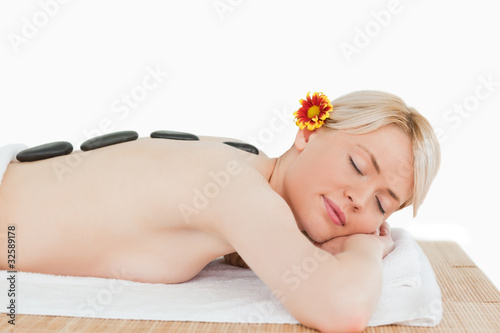 Cute blonde woman relaxing with hot stones on her back