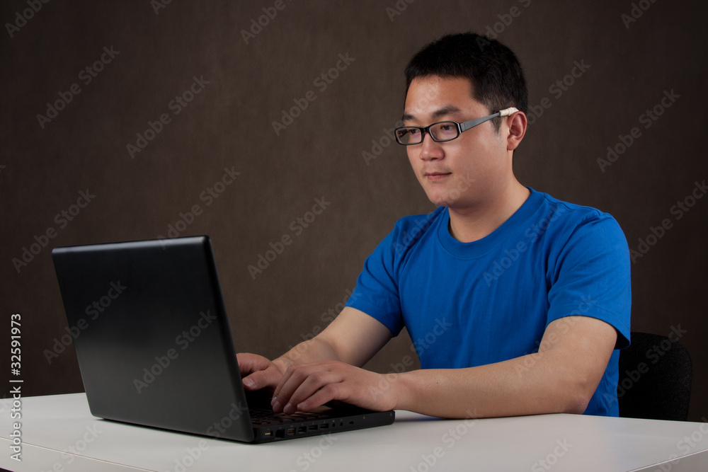 young asian man working on his laptop computer young asian man working on his laptop computer