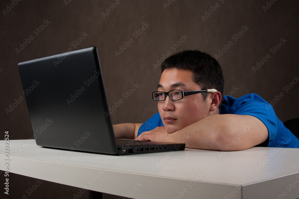 bored and tired young asian man working with his computer bored and tired young asian man working with his computer