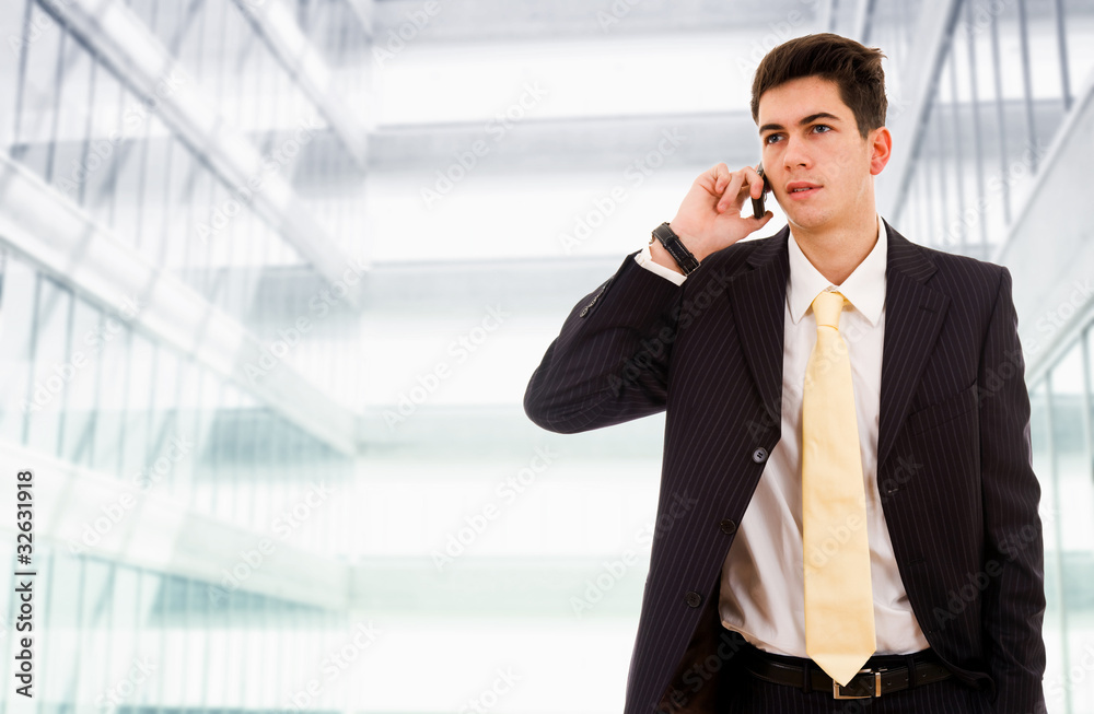 A young, handsome business man at the office building on phone A young, handsome business man at the office building on phone