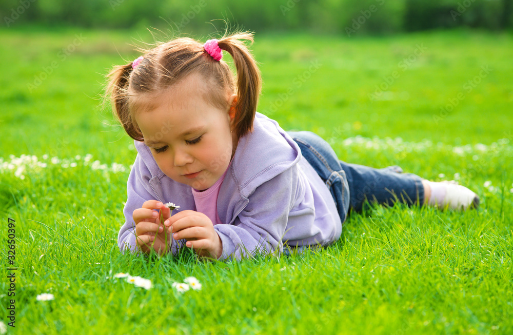 Little girl is laying on green meadow Little girl is laying on green meadow