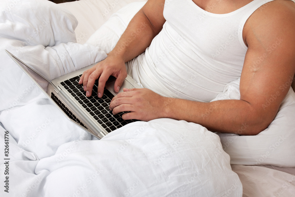 Fototapeta premium Man using laptop, sitting on bed