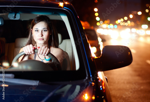 Young woman driving car in the night city