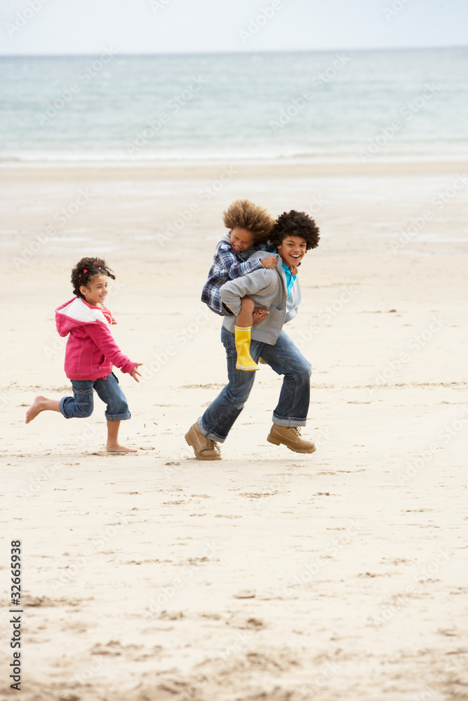 Happy children playing piggyback on beach Happy children playing piggyback on beach