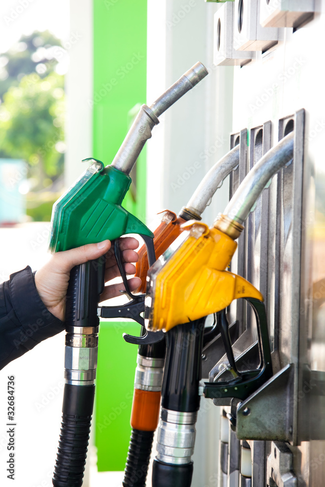 Man holding a gasoline nozzle in his hand Man holding a gasoline nozzle in his hand