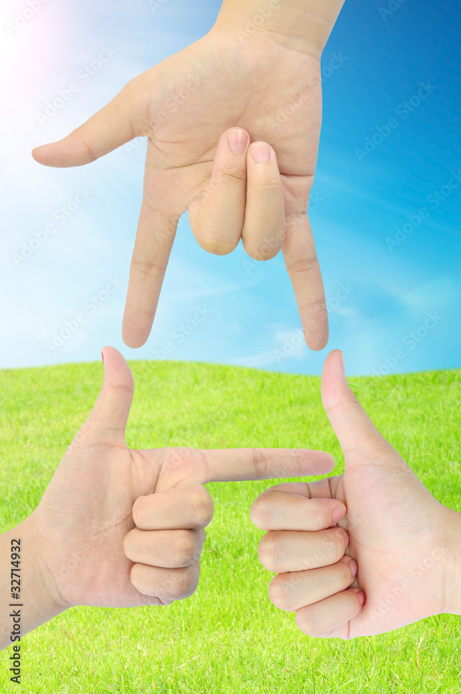 hand as triangle shape on fresh grass and blue sky hand as triangle shape on fresh grass and blue sky
