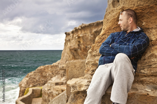 man laying on the rocks and watching the sunset