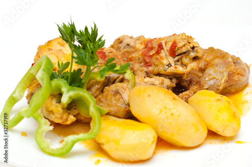Chicken and potatoes cooked in tomato sauce isolated on white