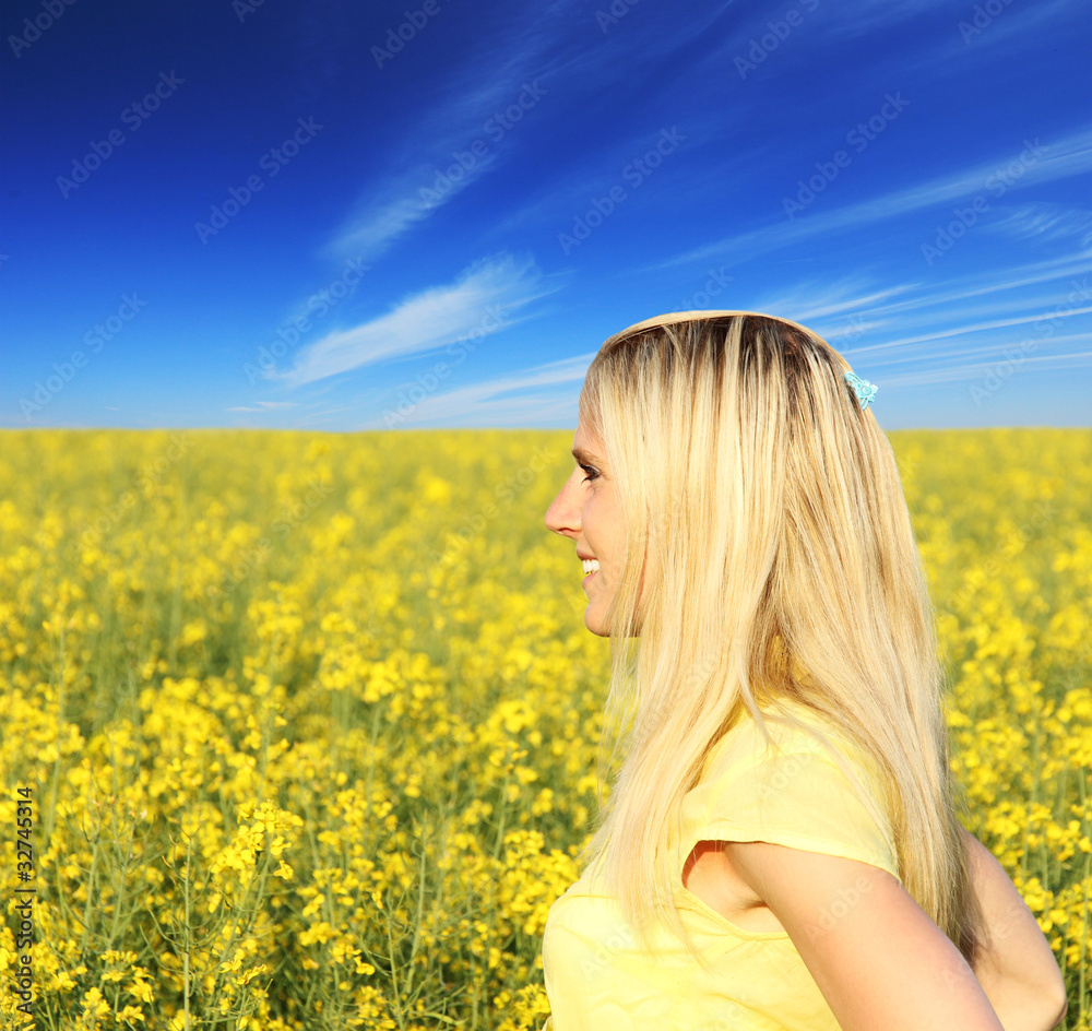 Beautiful blond girl looking on blooming field Beautiful blond girl looking on blooming field