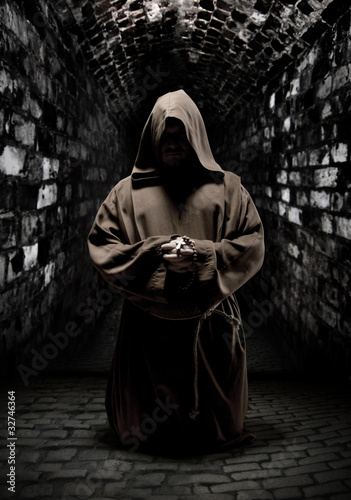 Tablou canvas Praying monk in dark temple corridor