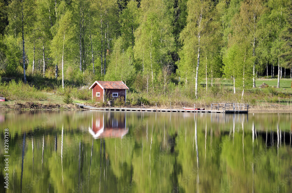 Obraz premium Calm lake reflection of house and trees in water