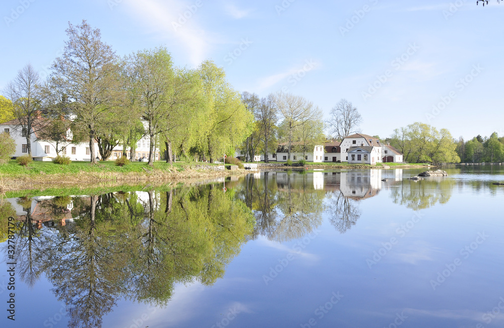 Calm lake reflection of house and trees in water
