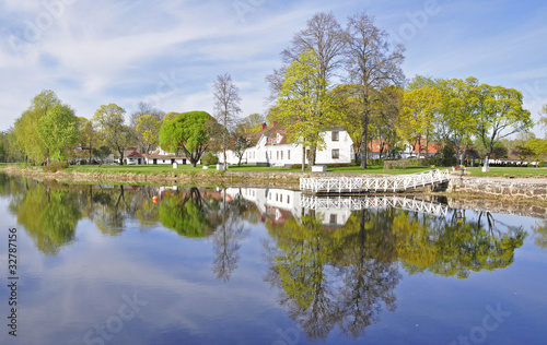 Calm lake reflection of house and trees in water