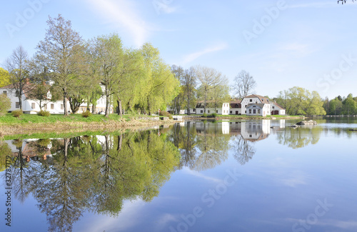 Calm lake reflection of house and trees in water © Conny Sjostrom
