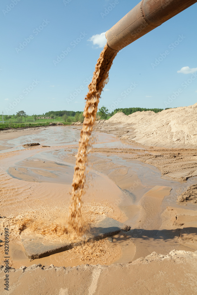 Вода с песком выливается из трубы.