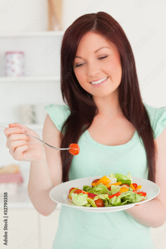 Beautiful red-haired woman enjoying a mixed salad in the kitchen Beautiful red-haired woman enjoying a mixed salad in the kitchen