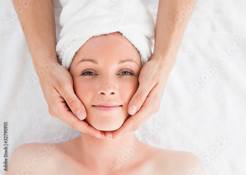 Closeup of a pretty red-haired woman receiving a massage in a sp