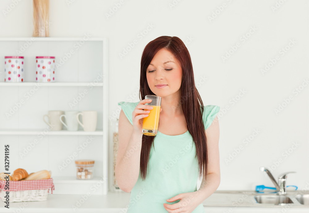 Attractive red-haired woman enjoying a glass of orange juice in Attractive red-haired woman enjoying a glass of orange juice in