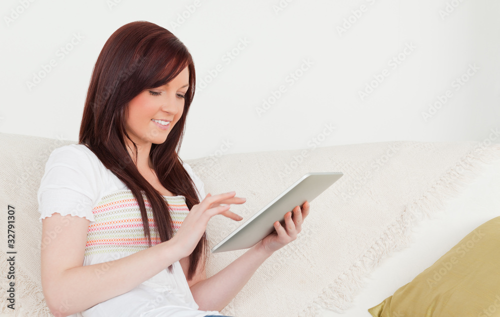 Good looking red-haired woman relaxing with her tablet while sit Good looking red-haired woman relaxing with her tablet while sit