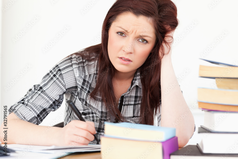 Attractive red-haired girl being upset while studying for an exa Attractive red-haired girl being upset while studying for an exa