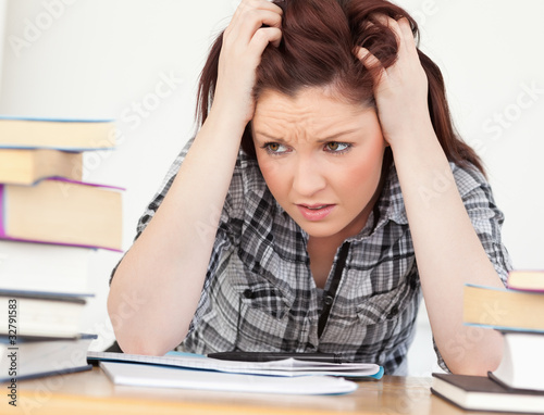 Attractive red-haired female being upset while studying for an e