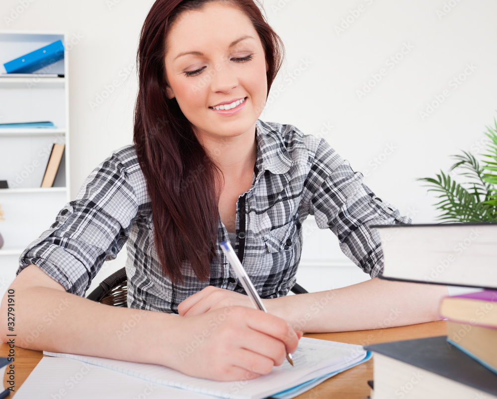 Lovely red-haired female studying at her desk Lovely red-haired female studying at her desk