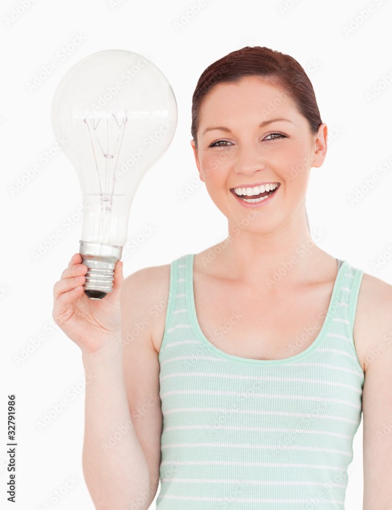 Gorgeous red-haired female holding a light bulb while standing Gorgeous red-haired female holding a light bulb while standing