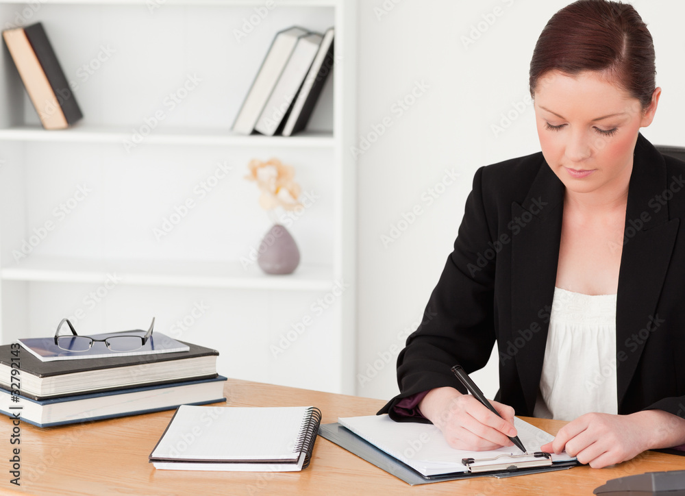 Attractive red-haired woman in suit writing on a notepad Attractive red-haired woman in suit writing on a notepad