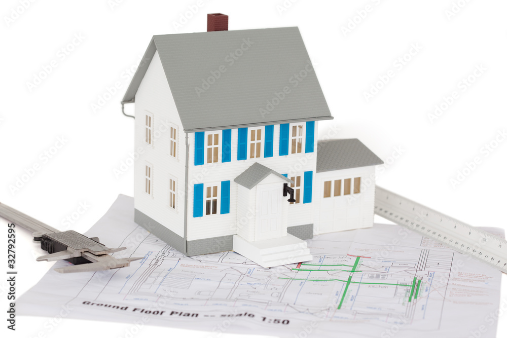 Closeup of toy house model and caliper on a ground floor plan Closeup of toy house model and caliper on a ground floor plan