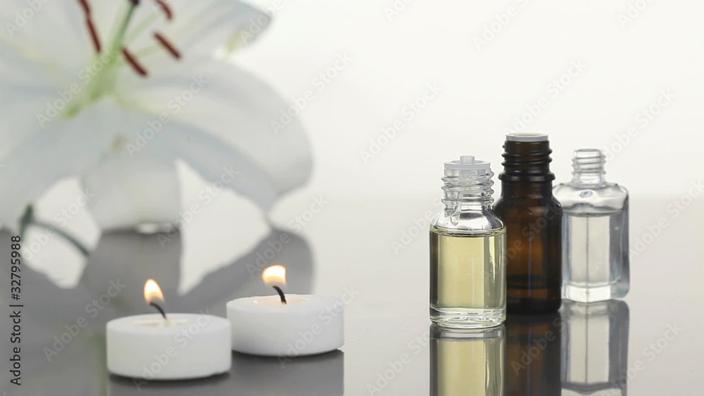 Lighted white candles near lotion flasks Lighted white candles near lotion flasks