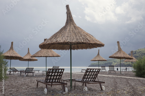 Fototapeta Naklejka Na Ścianę i Meble -  Straw Umbrellas with Sun Loungers on Beach